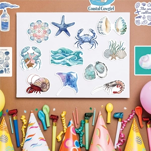 Flat lay of watercolor blue ocean stickers featuring crab, starfish, and sea shells