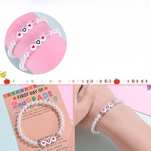Détail de bracelets en perles blanches avec perles cœur et guide de taille pour cadeau école