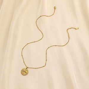 Detailed view of Taurus zodiac coin pendant on gold beaded stainless steel chain