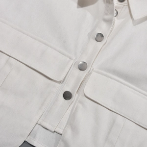 Détail de la texture en coton sergé blanc et des boutons métalliques sur la veste