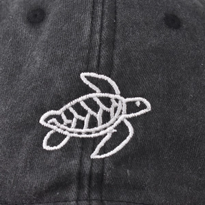 Vintage washed charcoal baseball cap with a detailed white sea turtle embroidery