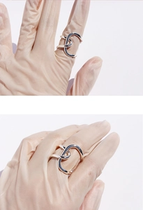 Macro shot of silver knotted wide band ring on beige glove showing sleek metal texture