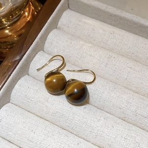 Close-up of golden tiger eye earrings with polished brown stone beads in a gift box