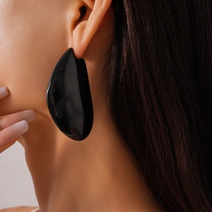 Vue rapprochée de grandes boucles d'oreilles irrégulières en résine noire portées par un mannequin