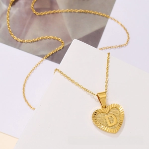 Detail of gold heart pendant with letter D engraving on a classic cable chain necklace