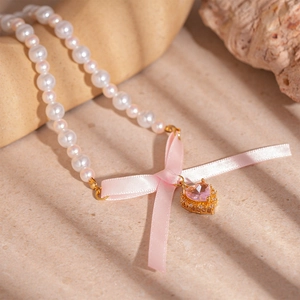 Elegant pearl necklace with pink ribbon bow and heart-shaped gemstone pendant