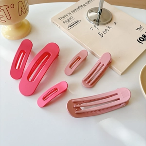 Flat lay of six matte pink hair clips and duckbill clips in a lifestyle setting