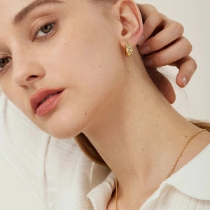 Classic gold twisted hoop earrings with a textured spiral design on model