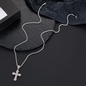 Close-up of hip hop silver cross pendant with sparkling stones on dark stone background