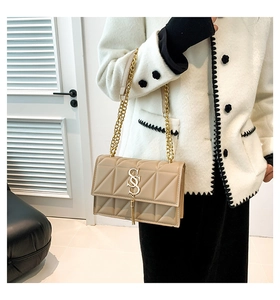 Detail of beige quilted chain bag with gold SS logo and elegant tassel pendant charm