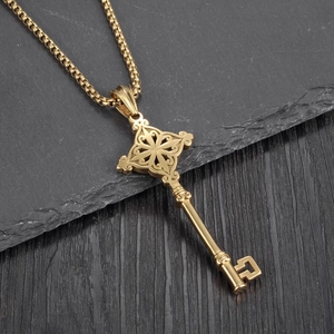 Detailed close-up of golden key pendant with intricate vintage cross patterns and round box chain