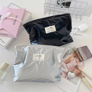 Close-up of shiny silver and black waterproof makeup bags with stylish woven labels