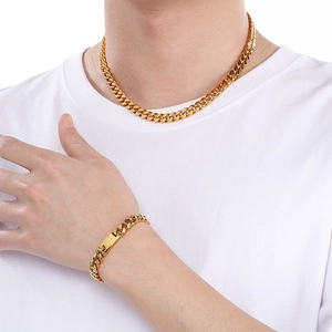Gros plan sur l'ensemble collier à mailles cubaines dorées et bracelet avec plaque sur mannequin