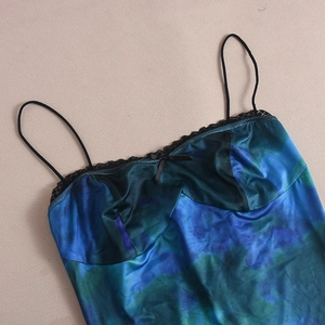 Détail du caraco en satin bleu canard avec dentelle noire et nœud sur le décolleté