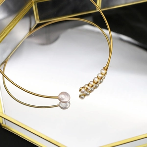 Elegant gold choker necklace with freshwater pearls and wire-wrapped design on mirror