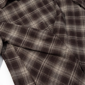 Détail de la chemise en flanelle à carreaux marron avec taille cintrée et texture de manche