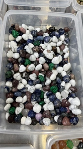 Detailed top view of bulk 15mm heart-shaped polished natural crystal stones in a clear box