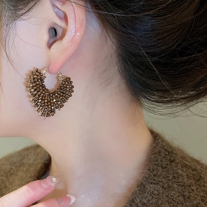 Close-up of model wearing dark brown crystal beaded heart earrings with vintage luxury style