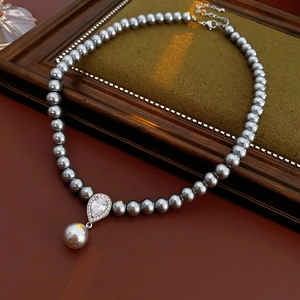 Macro shot of grey pearl necklace with zircon teardrop pendant on velvet display