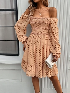 Close-up of brown polka dot dress featuring off-shoulder neckline and ruffled sleeve details