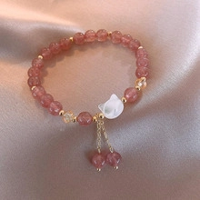 Detail of pink crystal beads and cat charm bracelet on elegant champagne satin background
