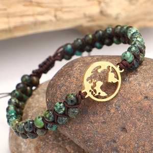 Detail view of African turquoise beads and gold world map charm on woven bracelet