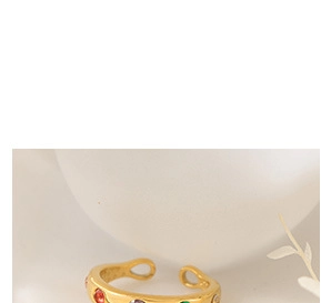 Gros plan d'une bague dorée large ornée de zircons multicolores sertis avec éclat