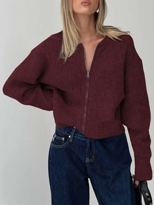 Close-up of a burgundy knit cardigan featuring a round neck and silver zipper detail