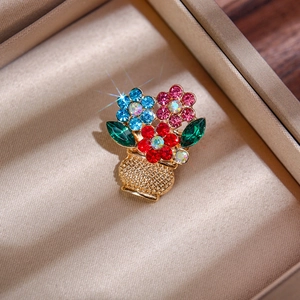 Detailed view of a gold flower basket brooch with colorful rhinestones in a jewelry box
