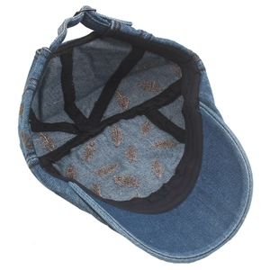 Detail of blue denim newsboy hat with brown fishbone print lining and metal strap