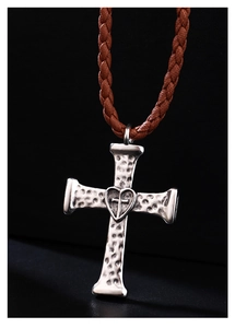 Macro shot of antique silver cross bolo tie pendant with heart detail and brown woven cord