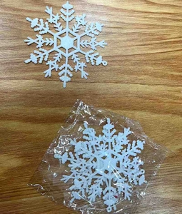 Close-up of white glittery snowflake ornaments on a wooden table with plastic packaging