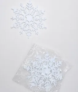 Close-up of white glittery snowflake ornaments on a wooden table with plastic packaging