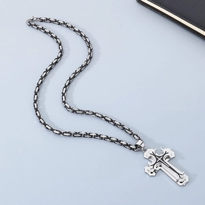 Close-up of triple-layered cross pendant in black and silver on a steel king chain