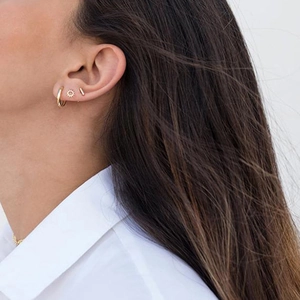 Close-up of golden sunflower stud earrings and hoops set on a model's ear