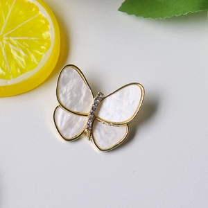 Macro detail of butterfly brooch with pearl luster wings and sparkling crystal inlay