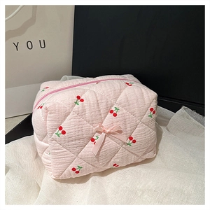 Pink quilted makeup bag featuring cherry embroidery and a small pink bow detail