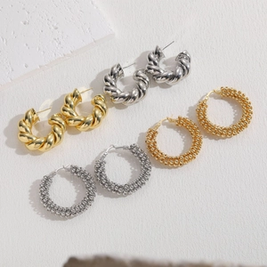 Golden and silver hoop earrings with twisted rope and bead textures on white background