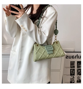 Detail of sage green quilted baguette bag featuring a thick woven shoulder strap and square buckle