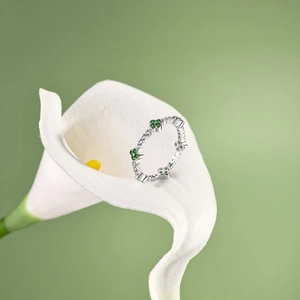 Close-up of S925 silver four-leaf clover ring with green zircon inside a white calla lily