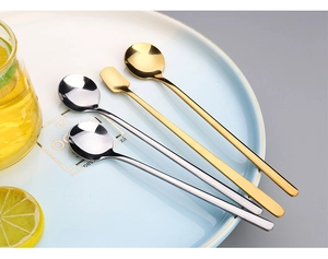 Macro shot of silver and gold stainless steel long handle spoons on a Budapest ceramic plate
