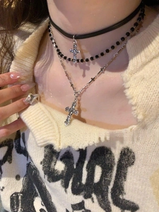 Detail shot of a leather choker with crystal cross pendants and a large square diamond ring