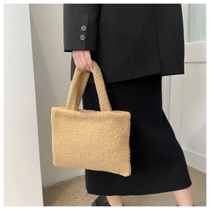 Detail shot of a beige faux shearling tote bag with soft teddy plush texture on a model