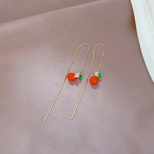 Detail of red cherry long tassel earrings with green crystal leaves on purple satin