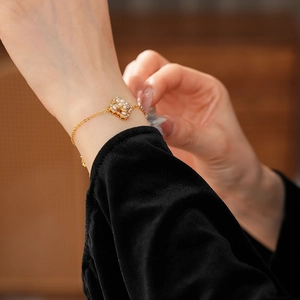 Détail d'un bracelet plaqué or avec pendentif carré orné de perles et de petits cristaux