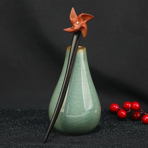Detail of a vintage sandalwood hair stick with a windmill head in a celadon vase