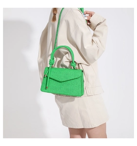 Detail shot of green woven texture and twisted rope handle on a stylish commute handbag