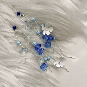 Detail view of elegant blue glass bead flower tassel earrings on white faux fur