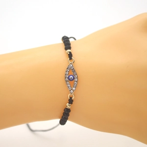Adjustable woven bracelet with black faceted beads and evil eye pendant on model