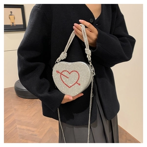 Dettaglio borsa a cuore in strass con motivo a freccia in cristallo rosso e catena